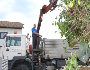 Ein Mitarbeiter von LINZ AG ABFALL hebt mit einem Kran Grünschnitt und Gartenabfälle in einen Container