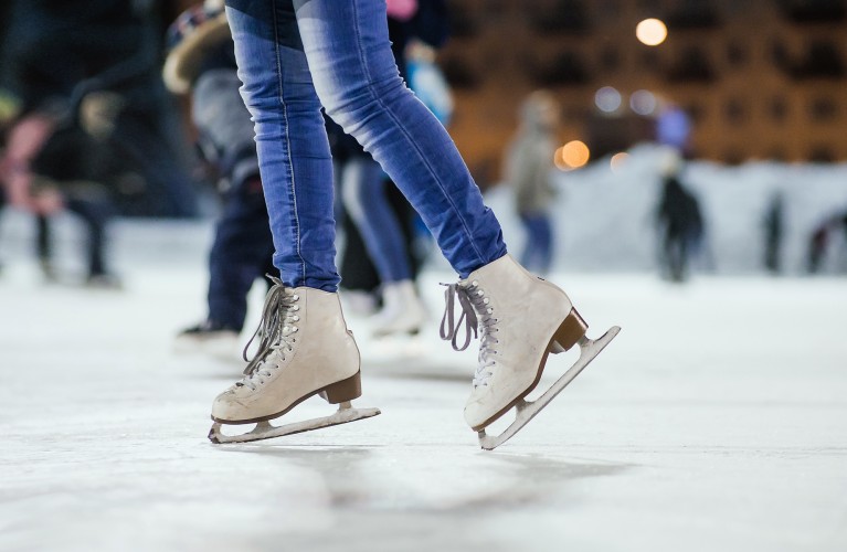 Frau mit Schlittschuhen auf der Eislauffläche