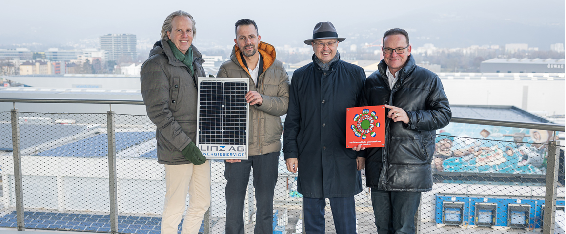 Vertreter der Linz AG und der Sparkasse Oberösterreich stehen nebeneinander und halten ein Photovotaik-Panle und ein Bild des Umweltzeichens in Händen