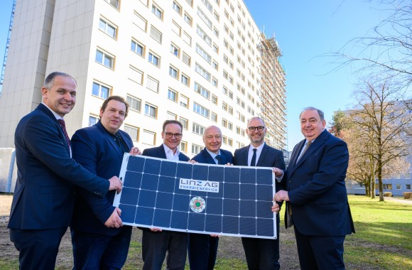 Die Projektpartner des Wist-Heims und der Linz-Energieservice GmbH stehen vor dem Wist-Heim und halten ein Solarpaneel