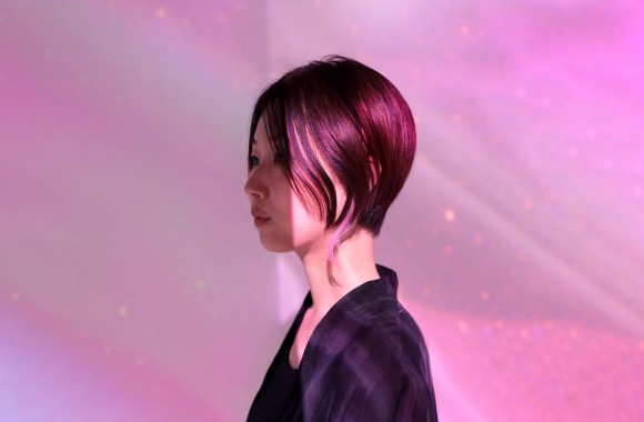 Eine rothaarige Frau (die Künstlerin Akiko Nakayama) asiatischer Herkunft vor rosa-farbenem Hintergrund. Copyright: Haruka Akagi