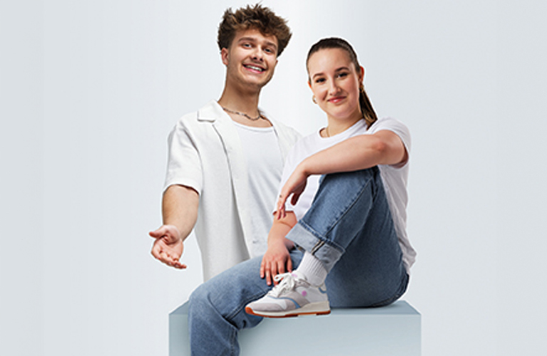 Ein Mädchen und ein Bursche, beide Lehrlinge in der Linz AG, lächeln in die Kamera. Rund um das Mädchen ist eine Sprechblase zu sehen mit der Aufschrift "Bereit für eine Lehre?" mit Emojis.