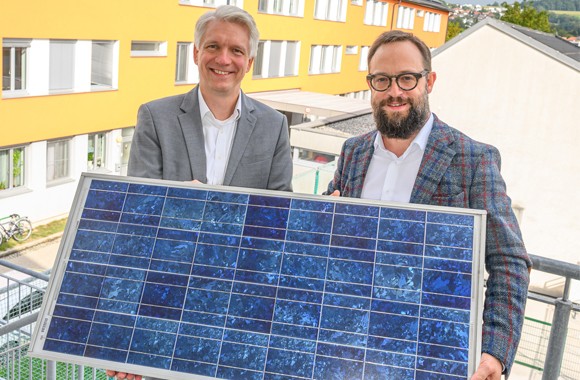 LINZ AG Vorstandsdirektor Mag. DI Josef Siligan und Caritas Direktor Stefan  Pimmingstorfer halten ein Photovoltaik-Paneel in der Hand