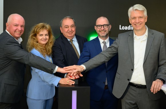 Die Personen Markus Past, Jutta Rinner, Erich Haider, Dietmar Prammer und Josef Siligan stehen vor einer Werbefläche der Telekom und drücken gemeinsam auf einen roten Startknopf.
