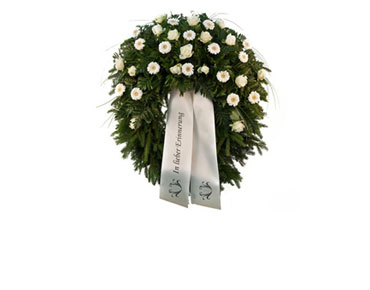 grüner Kranz mit weißen Gerbera und weißen Rosen, dazu eine weiße Schleife mit Aufschrift "in lieber Erinnerung"